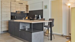 Ett modernt kök med en central köksö, inbyggda vitvaror och en bardisk med barstolar.