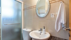Un baño con inodoro, lavabo, espejo y toallero.