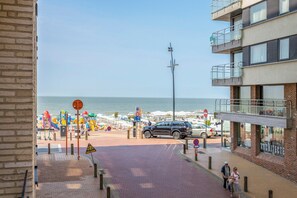 A coastal street with a beach in the background, a pedestrian crossing, and a building with a sign reading "ARCHITECTE". - Apartment in Blankenberge Near the Beach (Blankenberge)