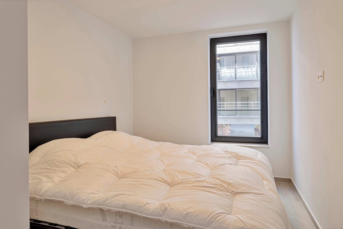 Ein Schlafzimmer mit einem Bett, einem Fenster und einer weißen Wand.
