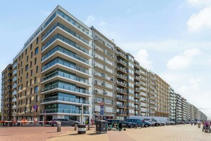 A multi-story residential building with balconies, a parking sign, and a pedestrian walkway. - Apartment in Blankenberge Near the Beach (Blankenberge)