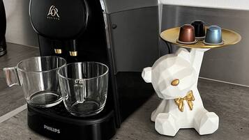 Een koffiezetapparaat, twee glazen en een decoratief berenbeeldje op een aanrecht.
