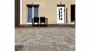 Un bâtiment doté de deux portes, d’une petite fenêtre et d’un patio avec deux chaises.