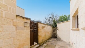 A narrow alleyway with stone walls and a metal gate.