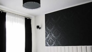 Una habitación de hotel moderna con una cama grande, una lámpara colgante y una pared con diseño.