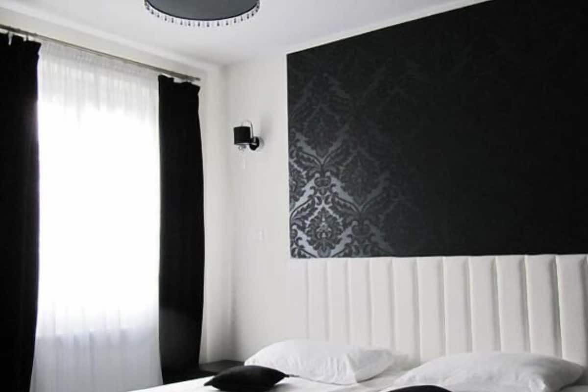 Una habitación de hotel moderna con una cama grande, una lámpara colgante y una pared con diseño.