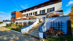 Un hotel moderno con una escalera que conduce a la entrada, sombrillas exteriores y un jardín con flores.