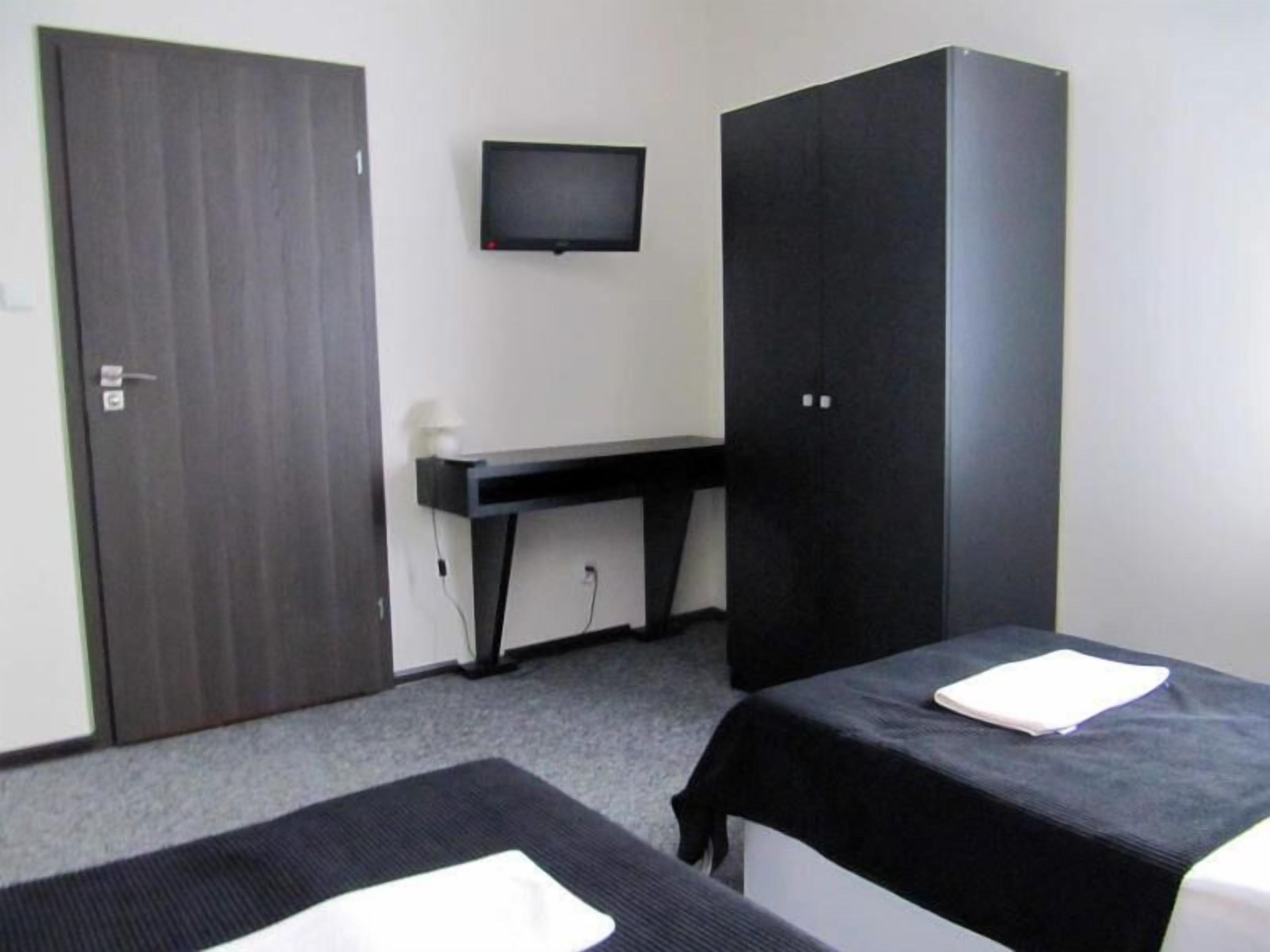 A room with two beds, a desk, a TV, and a wardrobe.