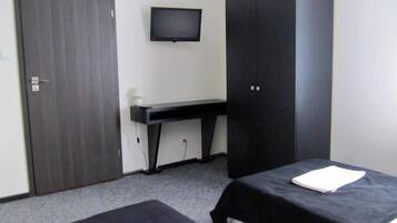 A room with two beds, a desk, a TV, and a wardrobe.