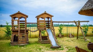 Un parque infantil de madera con dos casitas y un tobogán.
