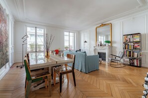 Ein geräumiges Zimmer mit einem großen Esstisch, einem Kamin und einem Bücherregal.