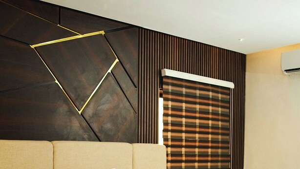 Una habitación de hotel moderna con una cama grande, un cabecero con diseños geométricos, una ventana con persianas y un equipo de aire acondicionado de pared.