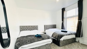 Ein Schlafzimmer mit zwei Betten, einem großen Spiegel und einem Fenster mit Vorhängen.