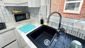A compact kitchen with a black sink, a microwave, and a dish rack.