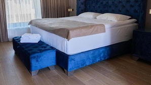 Ein ordentlich bezogenes Bett mit blauem Kopfteil, einem Nachttisch und einem passenden Ottomanen.