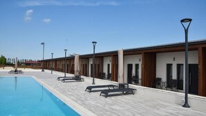 Ein Schwimmbecken mit Liegestühlen und einem überdachten Bereich mit Tischen und Stühlen.