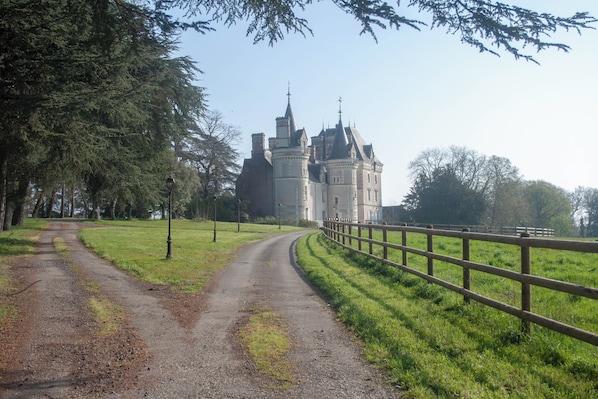 A pathway leading to a large, historic building with multiple towers and a prominent entrance. - Château de la Pervenchère - Gîte Marin (Casson)