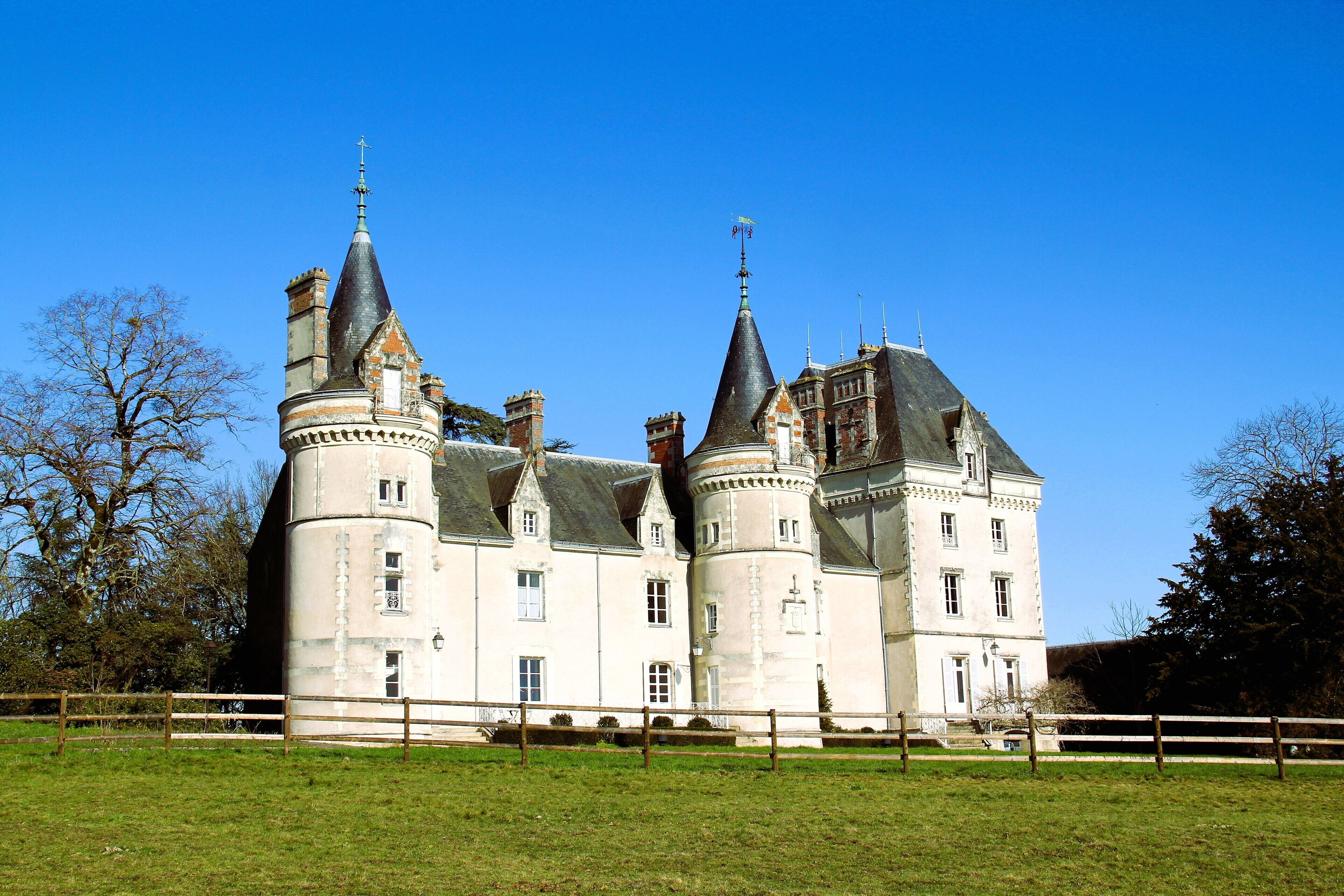 Een groot, historisch kasteel met meerdere torens en een verzorgd gazon.