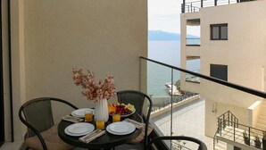 A balcony with a table set for breakfast, a vase with flowers, and a view of the sea. - Halina (Orikum)