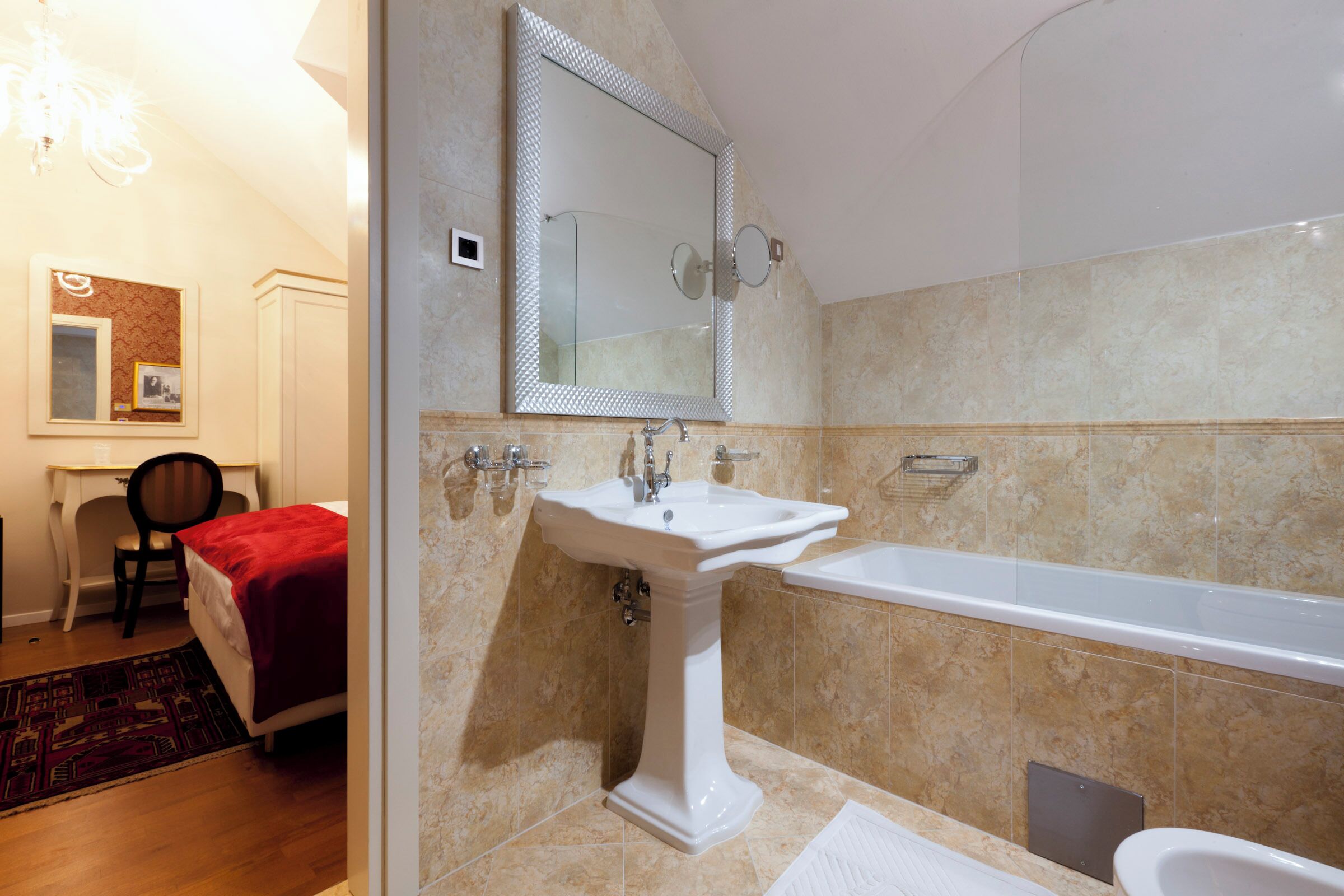 Un baño con lavamanos pedestal, un espejo grande y una bañera.