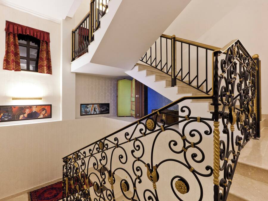 A multi-level interior with a staircase featuring ornate black metal railings and a beige carpet.