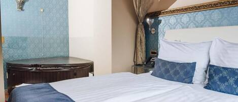 A hotel room with a bed, a desk, a telephone, and a wall-mounted light fixture.