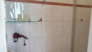 Ein Badezimmer mit Waschbecken, Ablagefläche aus Glas und Duschbereich.