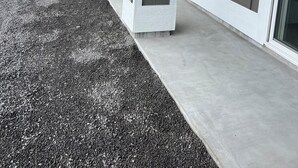 A building with a covered porch, a concrete ground, and a white fence in the background. - Spacious 4-bedroom , newly building in center of Hilo. (Hilo)