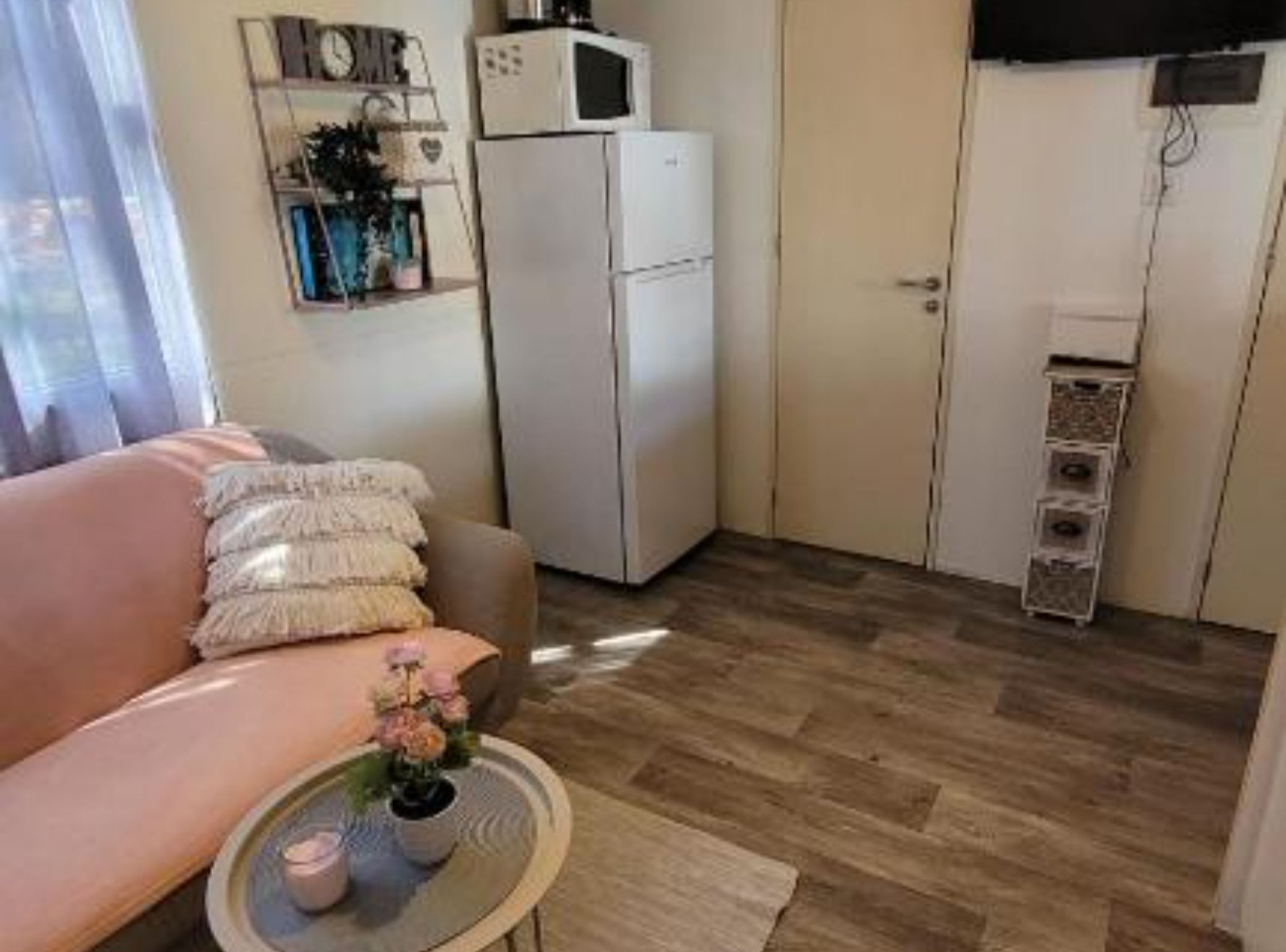 Un espacio habitable compacto con sofá, una mesita con una vela, microondas y refrigerador.