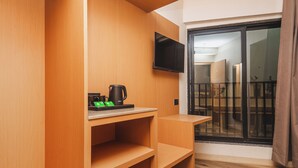 Ein Zimmer mit einem Holzkasten, einem flachbildfernseher an der Wand und einer Schiebeglastür, die zu einem Außenbereich führt.