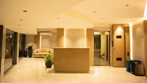 Eine moderne Hotelhalle mit einer Rezeption, einer Sitzecke und einer Zimmerpflanze.