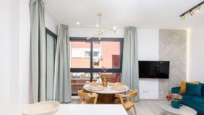 Et moderne spiseområde med et rundt bord, stole og en vase med blomster.