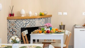 A dining area with a tiled backsplash, a white table set with plates, glasses, and a vase of flowers.