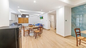 A modern living space with a dining area, kitchen, and a TV mounted on the wall. - Tenuta Marrocco House (Cursi)