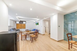 A modern living space with a dining area, kitchen, and a TV mounted on the wall. - Tenuta Marrocco House (Cursi)