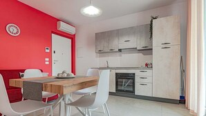 Een moderne keuken met witte kasten, een houten eettafel en een rode accentmuur.