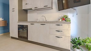 A modern kitchen with a built-in oven, a stainless steel range hood, and a flat-screen TV mounted above the counter. - Homiday - Albatros 2, Two Bedroom Apartment on the Ground Floor (Alba Adriatica)