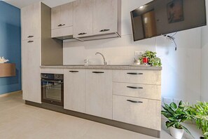 A modern kitchen with a built-in oven, a stainless steel range hood, and a flat-screen TV mounted above the counter. - Homiday - Albatros 2, Two Bedroom Apartment on the Ground Floor (Alba Adriatica)