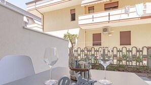 A table with two wine glasses and a 'Relax' sign, set against a building with balconies and a fence. - Homiday - Albatros 3, Two Bedroom Apartment on the Ground Floor (Alba Adriatica)
