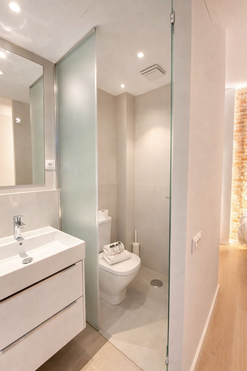 A modern bathroom with a glass shower enclosure, a white sink, and a toilet.