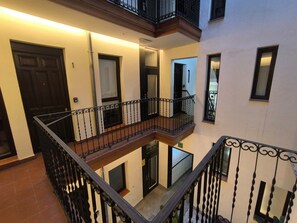 Um edifício residencial com vários níveis, varandas, uma escadaria central e uma porta.