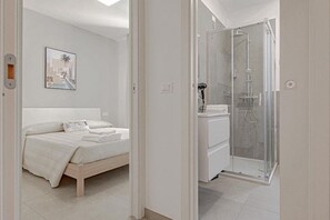 A bedroom with a bed, a shower, and a bathroom. - Homiday - Albatros 4, Two Bedroom Apartment on the Ground Floor (Alba Adriatica)