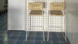 Een kitchenette met witte kastjes, een blauwe vaas en twee rieten stoelen.