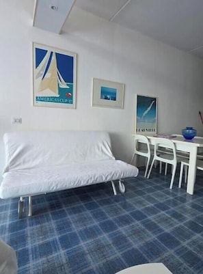A room with a white sofa, a dining table with chairs, and two framed pictures on the wall. - Dream apartment by the sea with panoramic terrace in Castro (Castro)