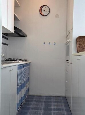 A small kitchen with a clock, a stove, and a blue patterned curtain. - Dream apartment by the sea with panoramic terrace in Castro (Castro)