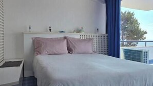 Een slaapkamer met een bed, nachtkastje, een wandairconditioner en een raam met gordijnen.