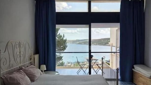 Une chambre avec un lit, une table et une vue sur un plan d’eau.