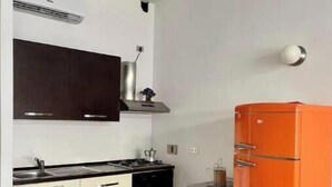 Une petite cuisine équipée d’une cuisinière, d’un évier et d’un réfrigérateur orange.