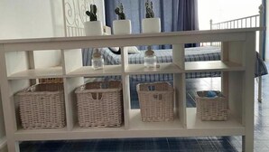 Une console blanche agrémentée de paniers en osier et d’objets décoratifs.