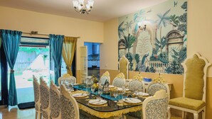 A dining area with a large table set for six, surrounded by ornate chairs. - Casa blu 4BHK Spacez Pool & Garden Villa (Bengaluru)